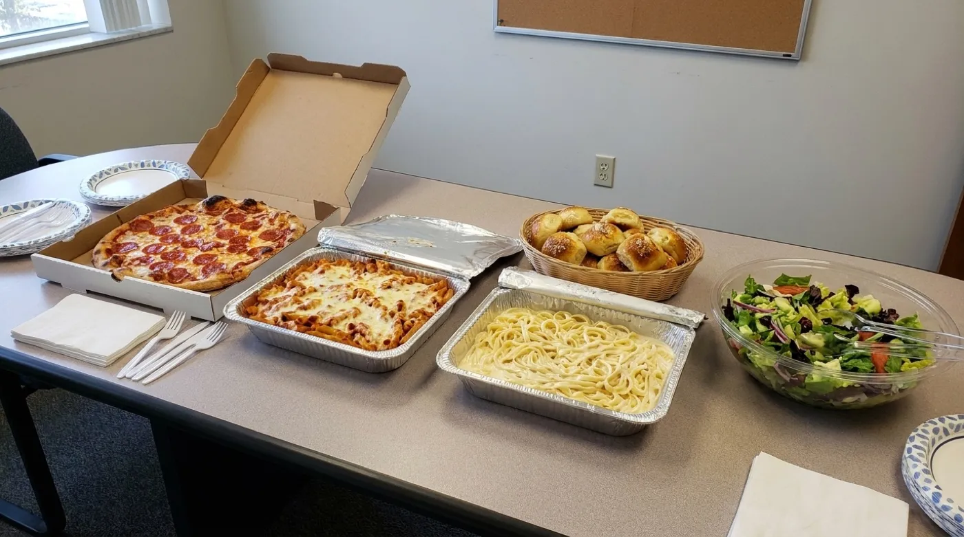 Italian office lunch catering spread with pasta trays, pizza and salad in an Alpharetta office
